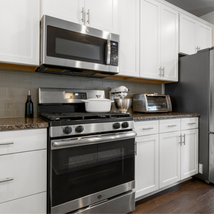  AppliancesA stainless steel stove and overhead stainless steel microwave setup in a fully furnished kitchen.